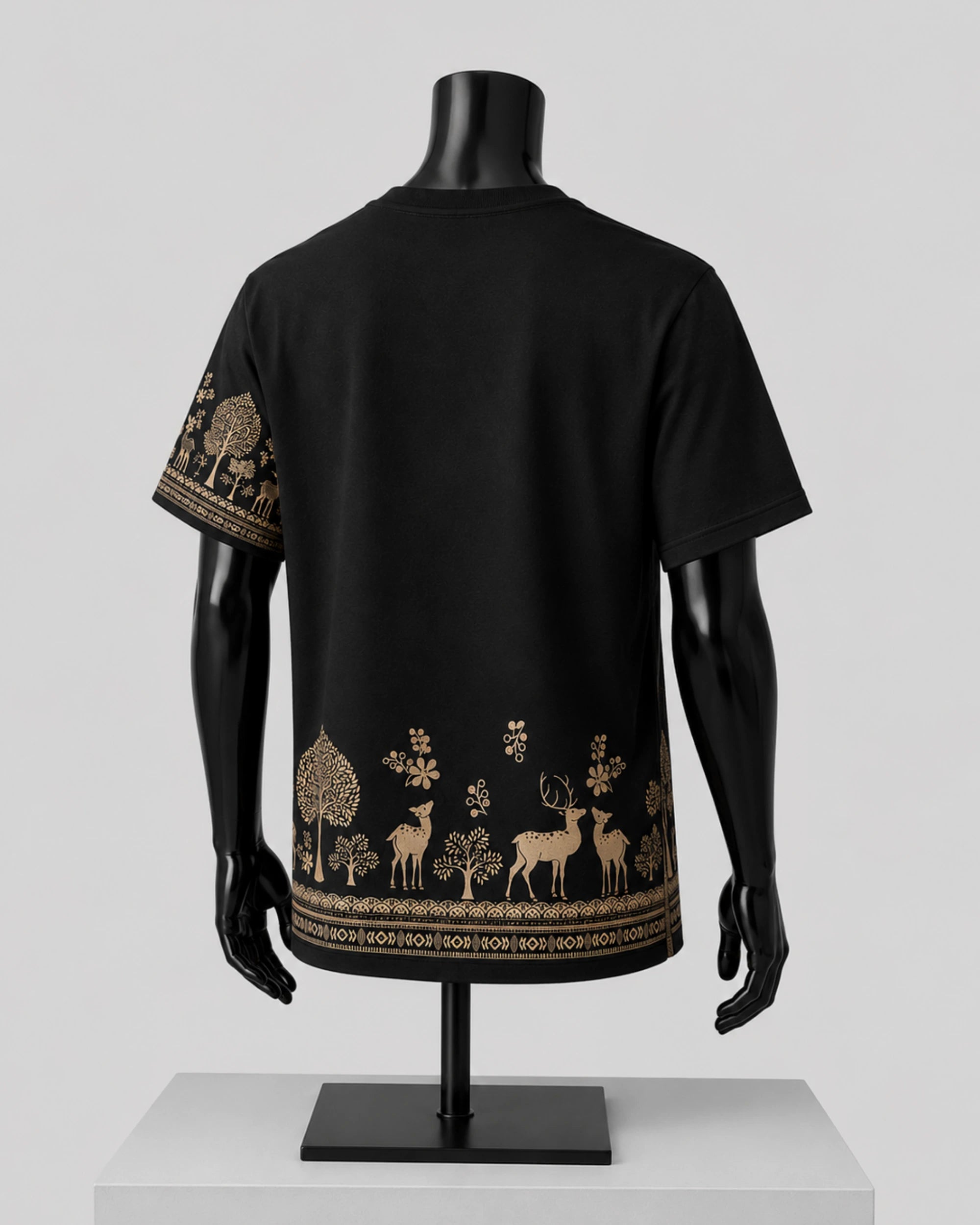 Black short-sleeve T-shirt displayed on a black mannequin, showing the back view with a decorative forest and deer print in beige along the lower hem and one sleeve.
