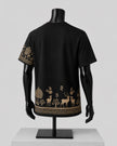 Black short-sleeve T-shirt displayed on a black mannequin, showing the back view with a decorative forest and deer print in beige along the lower hem and one sleeve.