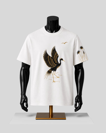 A white short-sleeve crewneck t-shirt displayed on a black mannequin torso. The shirt features a large graphic of a flying crane in black and gold on the front, with a smaller matching graphic on the left sleeve.