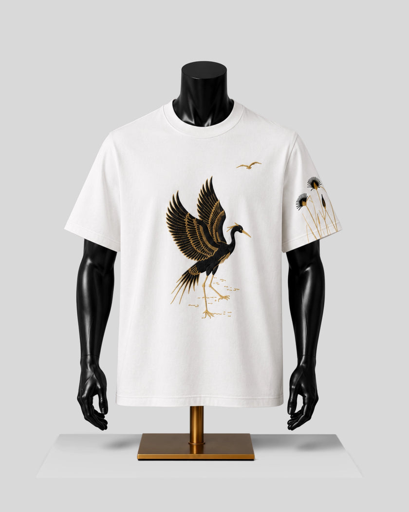 A white short-sleeve crewneck t-shirt displayed on a black mannequin torso. The shirt features a large graphic of a flying crane in black and gold on the front, with a smaller matching graphic on the left sleeve.