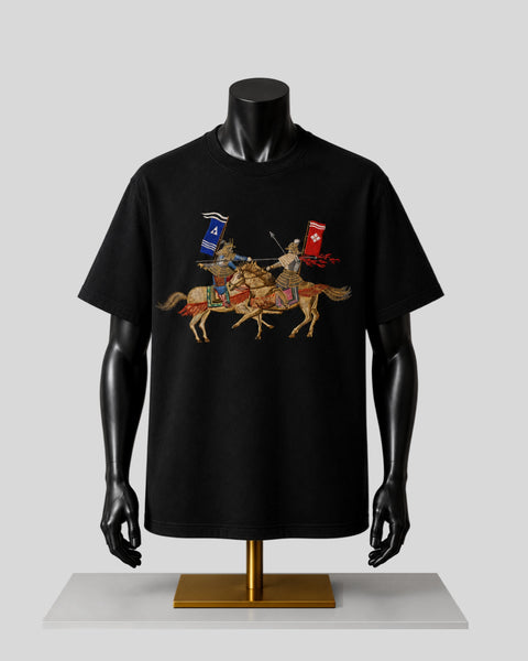 A black short-sleeve t-shirt displayed on a black mannequin torso with a gold stand, featuring a graphic print of two medieval knights on horseback with blue and red banners against a light gray background.