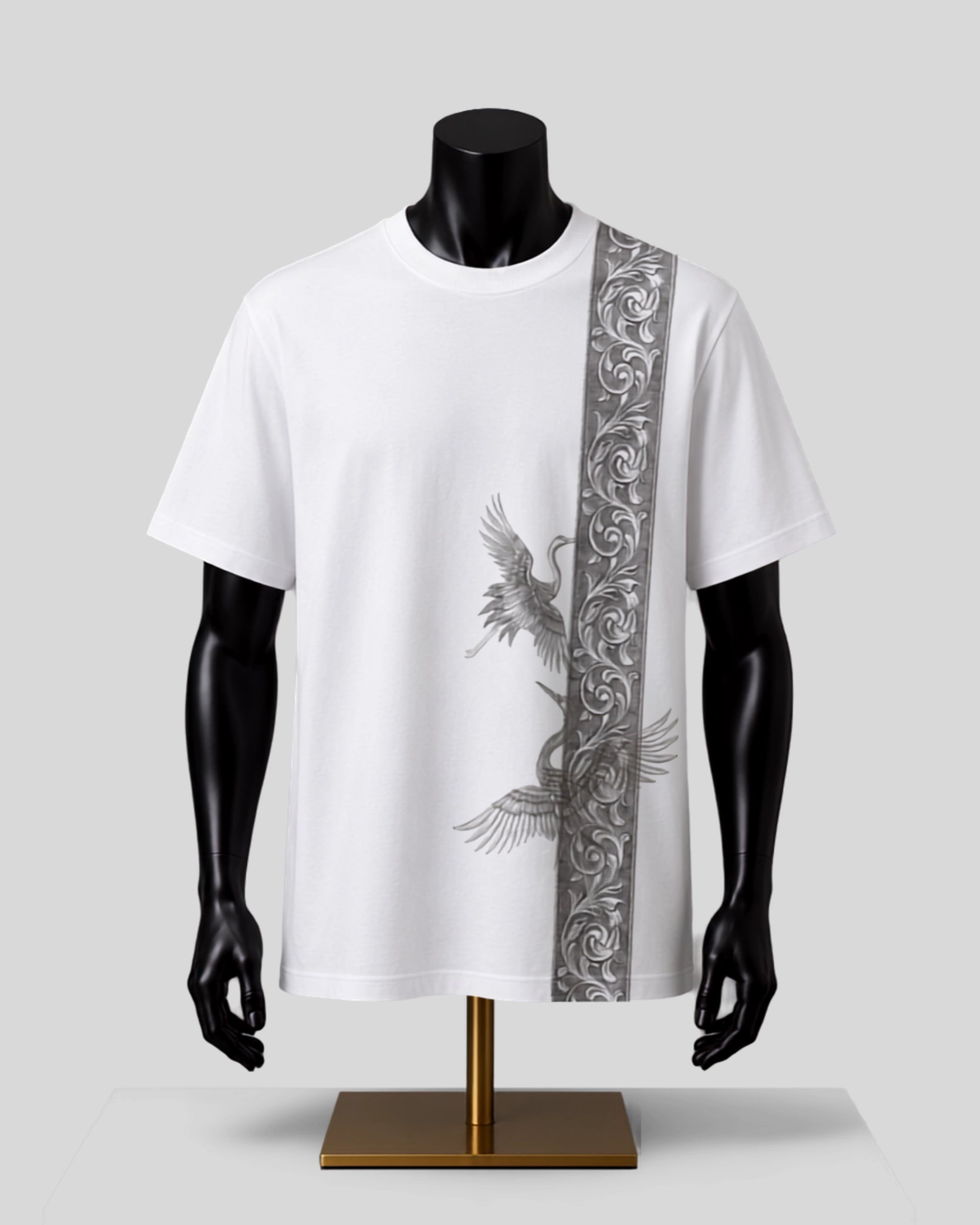 White short-sleeve t-shirt displayed on a black mannequin torso with a gold stand, featuring a vertical gray ornamental pattern on the right side and a gray bird motif on the front.