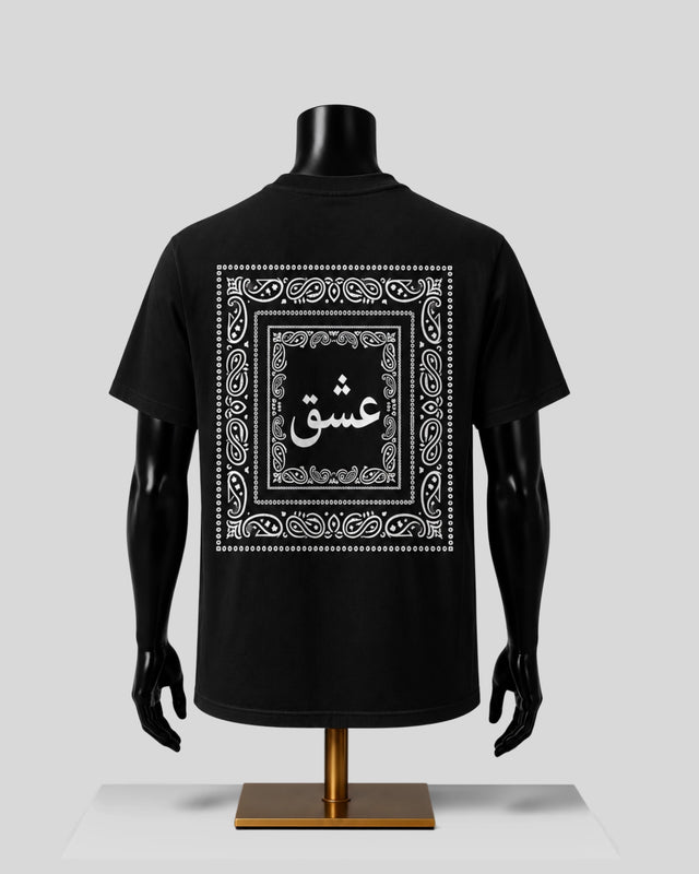 A black short-sleeve T-shirt displayed on a black mannequin torso with arms and a stand, shown from the back. The shirt features a large white ornate border graphic with Arabic calligraphy in the center.