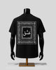 A black short-sleeve T-shirt displayed on a black mannequin torso with arms and a stand, shown from the back. The shirt features a large white ornate border graphic with Arabic calligraphy in the center.