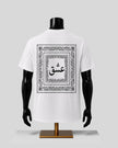White short-sleeve T-shirt displayed on a black mannequin torso, shown from the back. The shirt features a large black ornamental border graphic with Arabic calligraphy in the center, set against a light gray studio background.