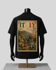 A black short-sleeve T-shirt displayed on a black mannequin torso with a gold stand, shown from the back. The shirt features a large vintage-style Italy travel stamp graphic with illustrations of the Colosseum, mountains, and Italian landscapes, along with the word 'ITALY' and a postmark.