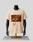 A beige short-sleeve graphic T-shirt displayed on a black mannequin torso with a gold stand against a light gray background. The shirt features the word 'KALAKAR' above a rectangular ornate pattern in red, gold, and brown, with three small flame-like motifs below.