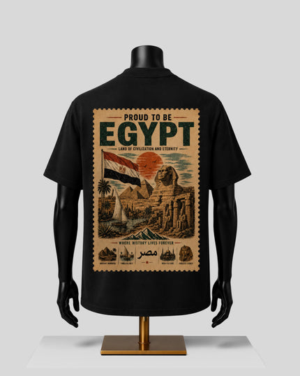 A black short-sleeve T-shirt displayed on a black mannequin torso, showing the back side with a large vintage-style Egyptian travel poster graphic. The graphic includes the text 'PROUD TO BE EGYPT' and an illustrated scene with the Egyptian flag, pyramids, and desert landscape in beige, brown, red, and green tones.