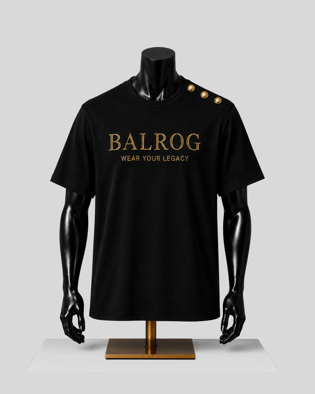 A black Balrog short-sleeve t-shirt displayed on a black mannequin torso with gold lettering on the chest and gold buttons on the shoulder, set against a light gray background.