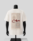 An off-white short-sleeve T-shirt displayed on a black mannequin torso, showing the back side. The shirt features a large rectangular graphic print of a beige and gray patterned rug with a bold red Arabic calligraphy design across the center.