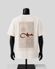 An off-white short-sleeve T-shirt displayed on a black mannequin torso, showing the back side. The shirt features a large rectangular graphic print of a beige and gray patterned rug with a bold red Arabic calligraphy design across the center.