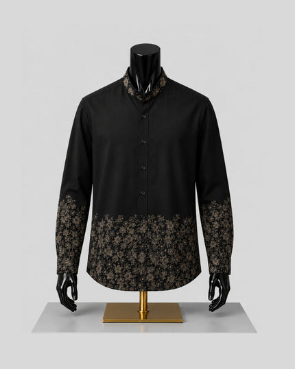 A black long-sleeve button-front shirt displayed on a black mannequin with a gold stand, featuring brown floral lace-like patterns at the collar, cuffs, and lower hem, against a light gray studio background.