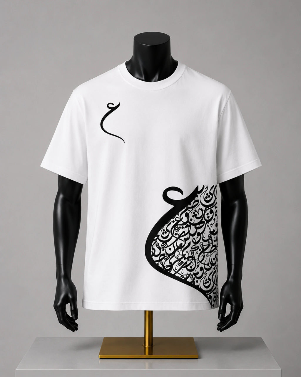 A white short-sleeve t-shirt displayed on a black mannequin torso with a gold stand against a neutral gray background. The shirt features a black Arabic calligraphy graphic, resembling a stylized crescent or abstract scroll, printed on the right side and a small matching calligraphy motif on the left chest.