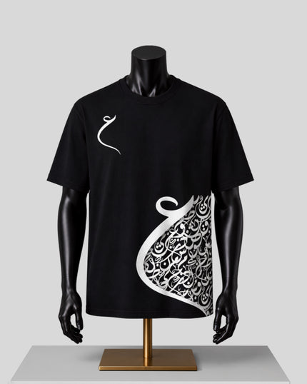 A black short-sleeve t-shirt displayed on a black mannequin torso with a gold stand against a light gray background. The shirt features a white Arabic calligraphy graphic on the right side and a small white calligraphy symbol on the left chest.