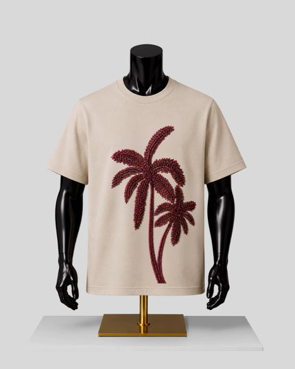 A beige short-sleeve crewneck T-shirt displayed on a black mannequin torso with a gold stand, featuring a large dark red palm tree graphic on the front.