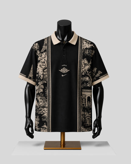 A black short-sleeve polo shirt displayed on a black mannequin torso with arms and a gold stand against a light gray studio background. The shirt has beige-and-black scenic vertical panels on both sides of the center, a beige collar, and a small central logo with Nike branding.