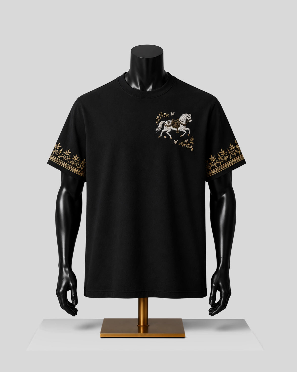A black short-sleeve t-shirt displayed on a black mannequin torso with a gold stand, featuring a white horse graphic on the left chest and gold patterned embroidery on both sleeves, set against a light gray background.