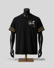 A black short-sleeve t-shirt displayed on a black mannequin torso with a gold stand, featuring a white horse graphic on the left chest and gold patterned embroidery on both sleeves, set against a light gray background.