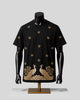 A black short-sleeve t-shirt displayed on a black mannequin torso with a gold stand, featuring gold embroidered floral motifs and a large peacock design across the lower front.