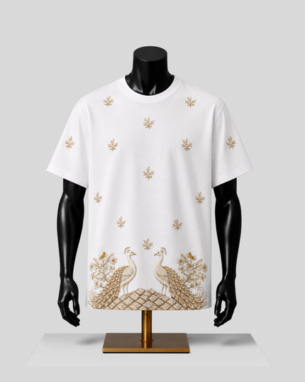 White short-sleeve crewneck T-shirt displayed on a black mannequin torso with a gold embroidered design featuring peacocks and floral motifs, set against a light gray background.