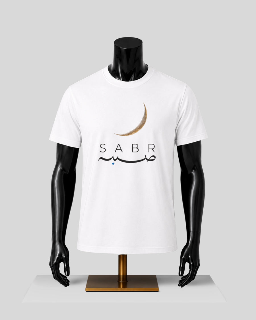 A white short-sleeve crewneck t-shirt displayed on a black mannequin torso with a gold stand, featuring a crescent moon and 'SABR' graphic on the chest, set against a light gray background.