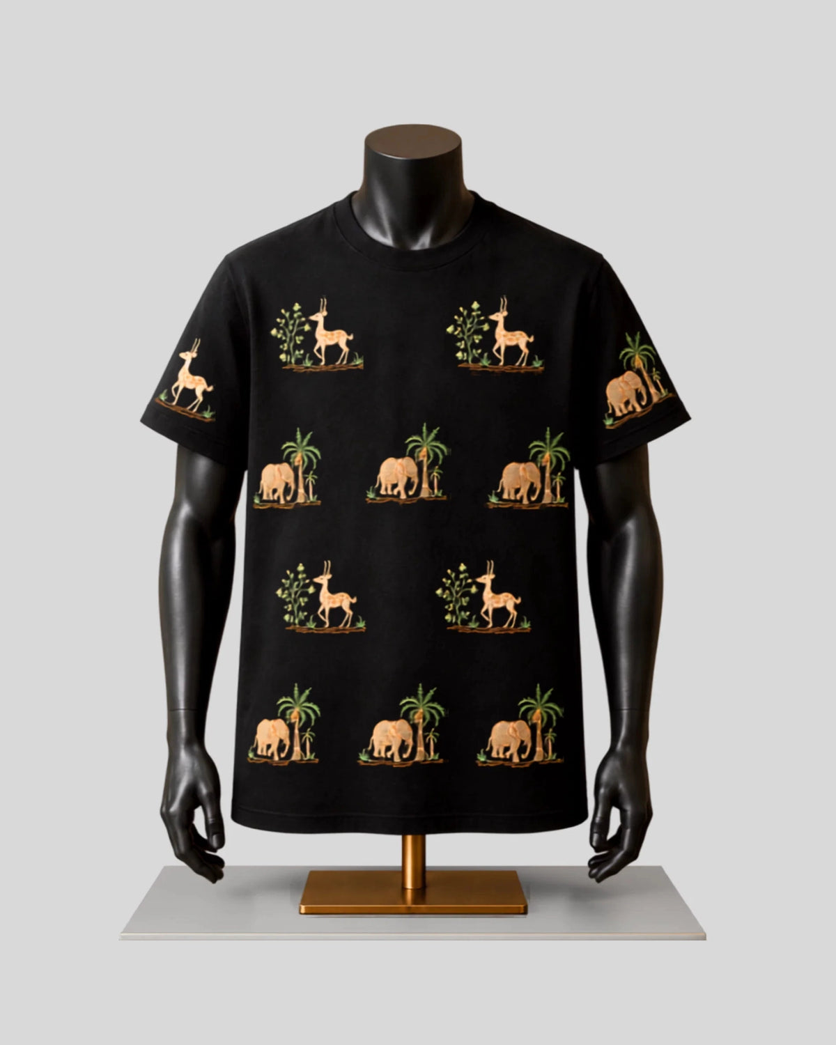 A black short-sleeve t-shirt displayed on a black mannequin torso with arms, featuring a repeating pattern of beige elephants, giraffes, and palm trees with green foliage, set against a light gray background.