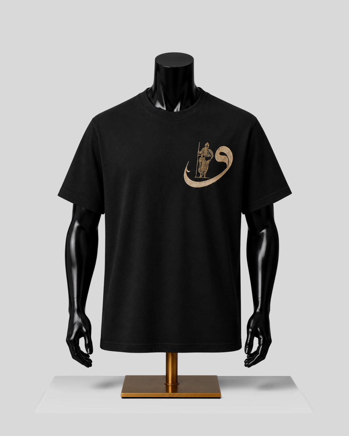 A black short-sleeve crewneck t-shirt displayed on a black mannequin torso with a gold graphic on the left chest, set against a light gray background.