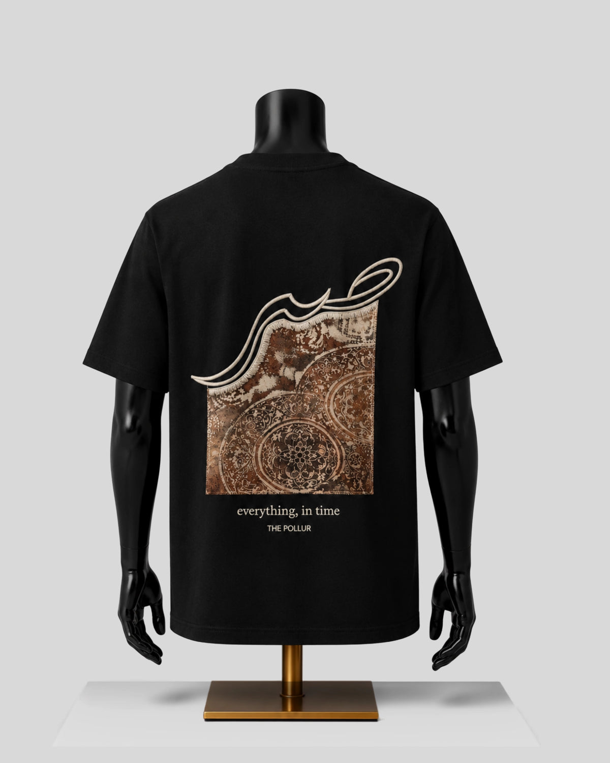 A black short-sleeve T-shirt displayed on a black mannequin torso, showing the back side with a large square graphic print in brown and beige tones. The graphic includes Arabic calligraphy and the text 'everything, in time' and 'THE POLLUR'.