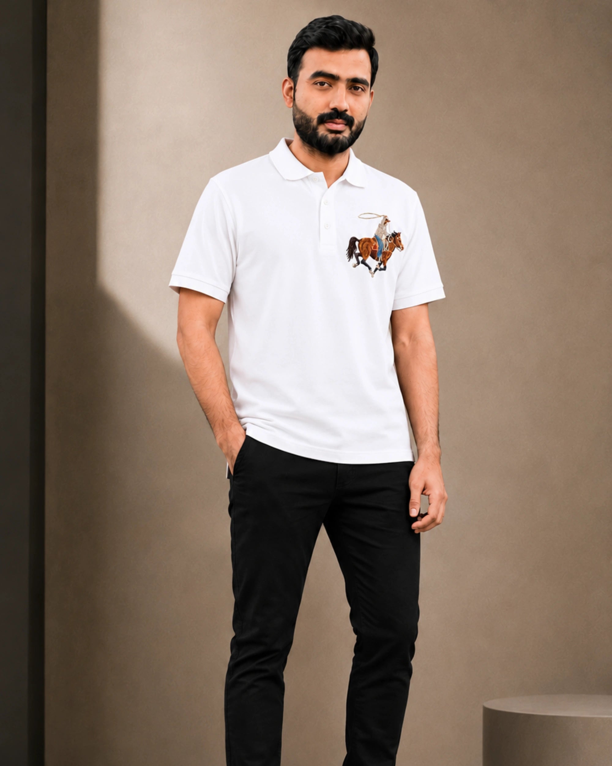 A man wearing a white short-sleeve polo shirt with a small embroidered polo player graphic on the left chest, paired with black pants, standing against a neutral beige background.