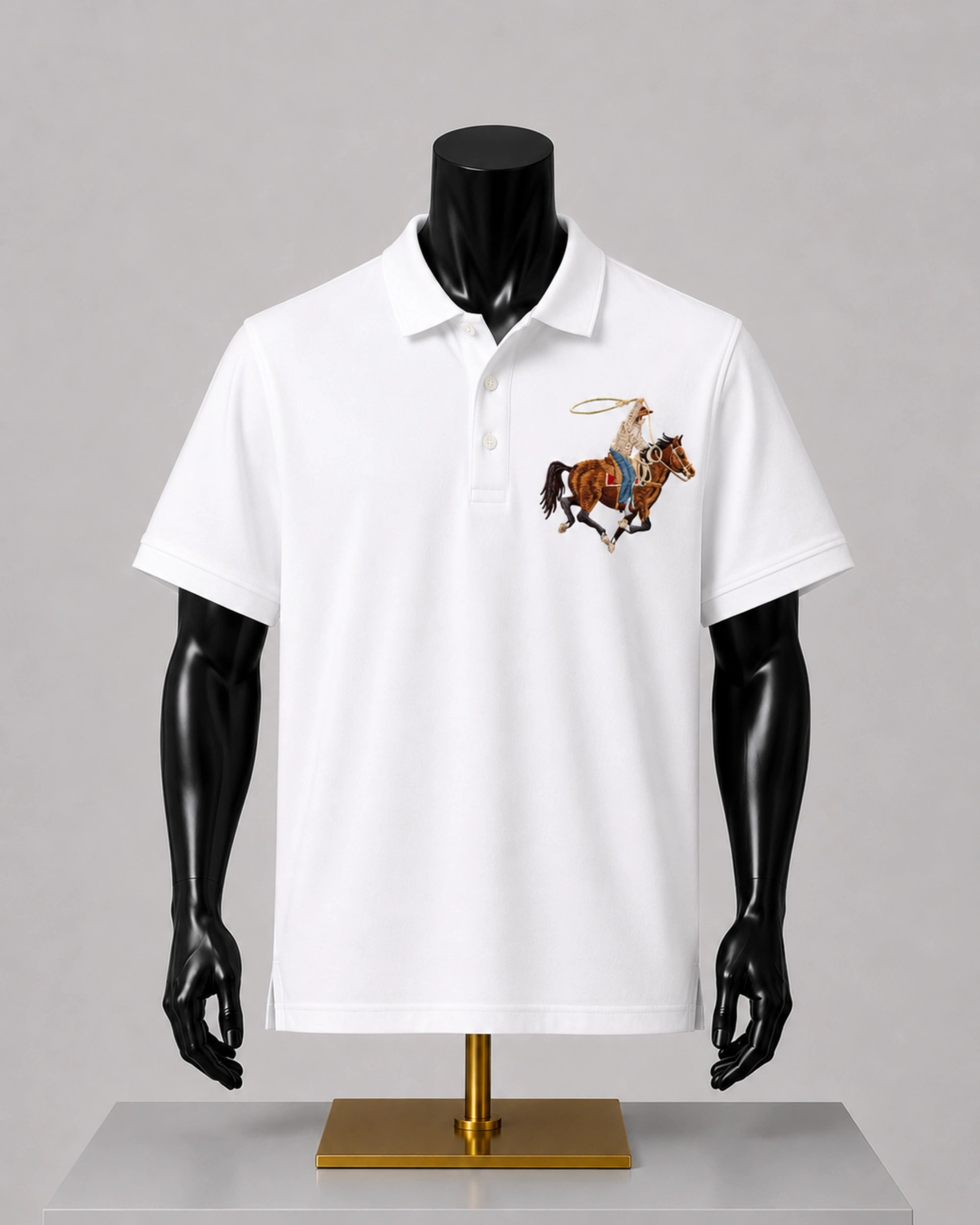 A white short-sleeve polo shirt displayed on a black mannequin torso with a gold stand, featuring a small embroidered cowboy on horseback graphic on the left chest.