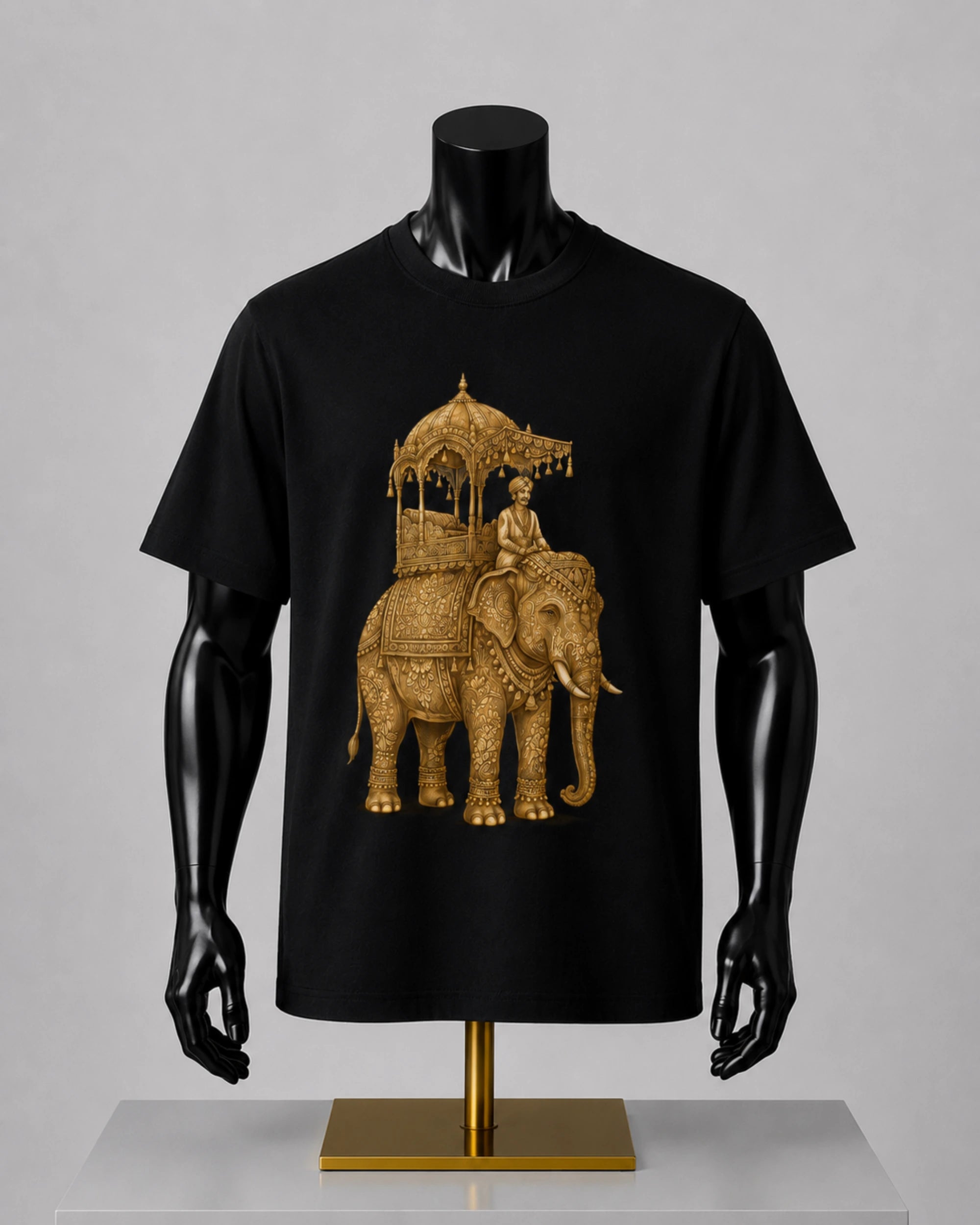 A black short-sleeve t-shirt displayed on a black mannequin torso with a gold-colored elephant and rider graphic printed on the front, set against a neutral gray background.