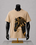 A beige short-sleeve t-shirt displayed on a black mannequin torso with a gold horse stand, featuring a graphic print of a black horse wearing ornate gold armor on the front.