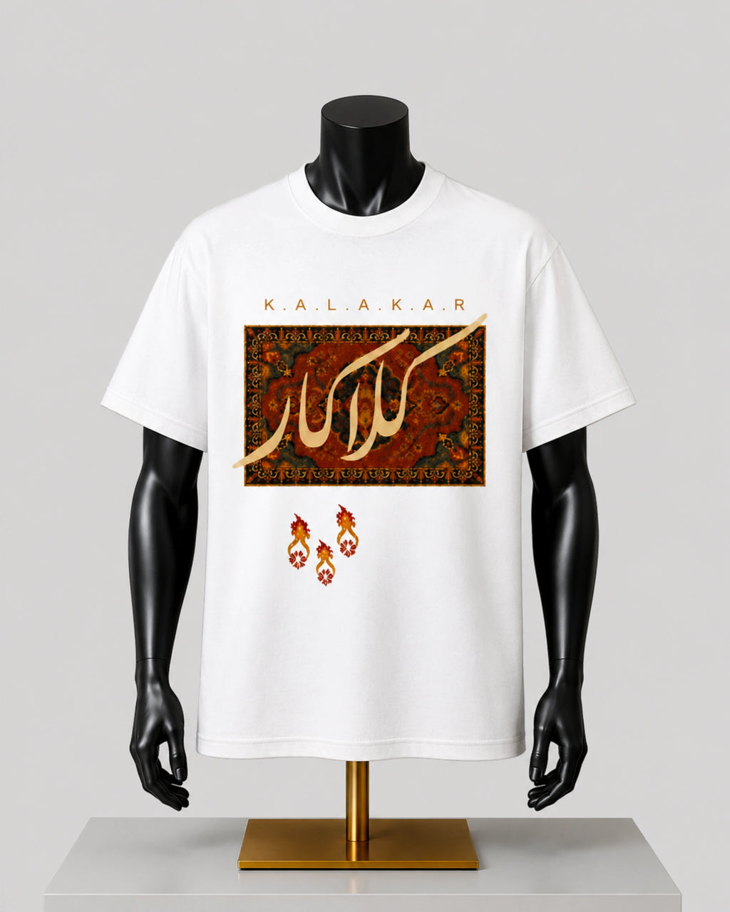 White short-sleeve graphic T-shirt displayed on a black mannequin torso with a gold stand, featuring Arabic calligraphy and the brand name KALAKAR on the front against a light gray background.