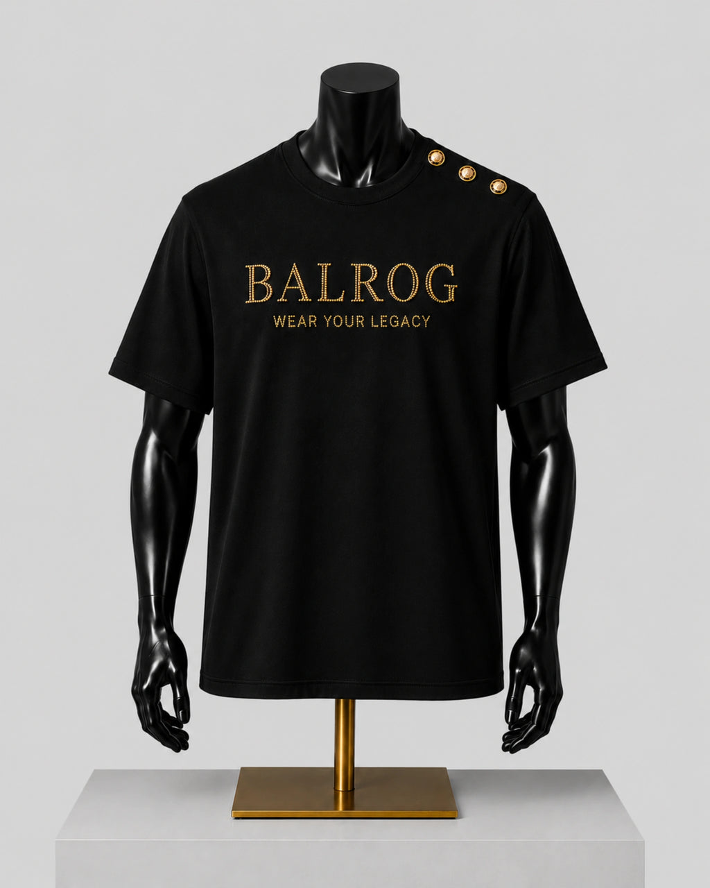 Black short-sleeve Balrog T-shirt displayed on a black mannequin torso with gold lettering on the chest and gold buttons on the shoulder, set against a light gray background.