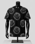 A black short-sleeve t-shirt with a white dotted rose pattern, displayed on a black mannequin against a light gray background.
