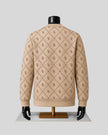 A beige knit sweater with an allover brown monogram pattern, displayed on a black mannequin torso with a gold stand against a light gray background.