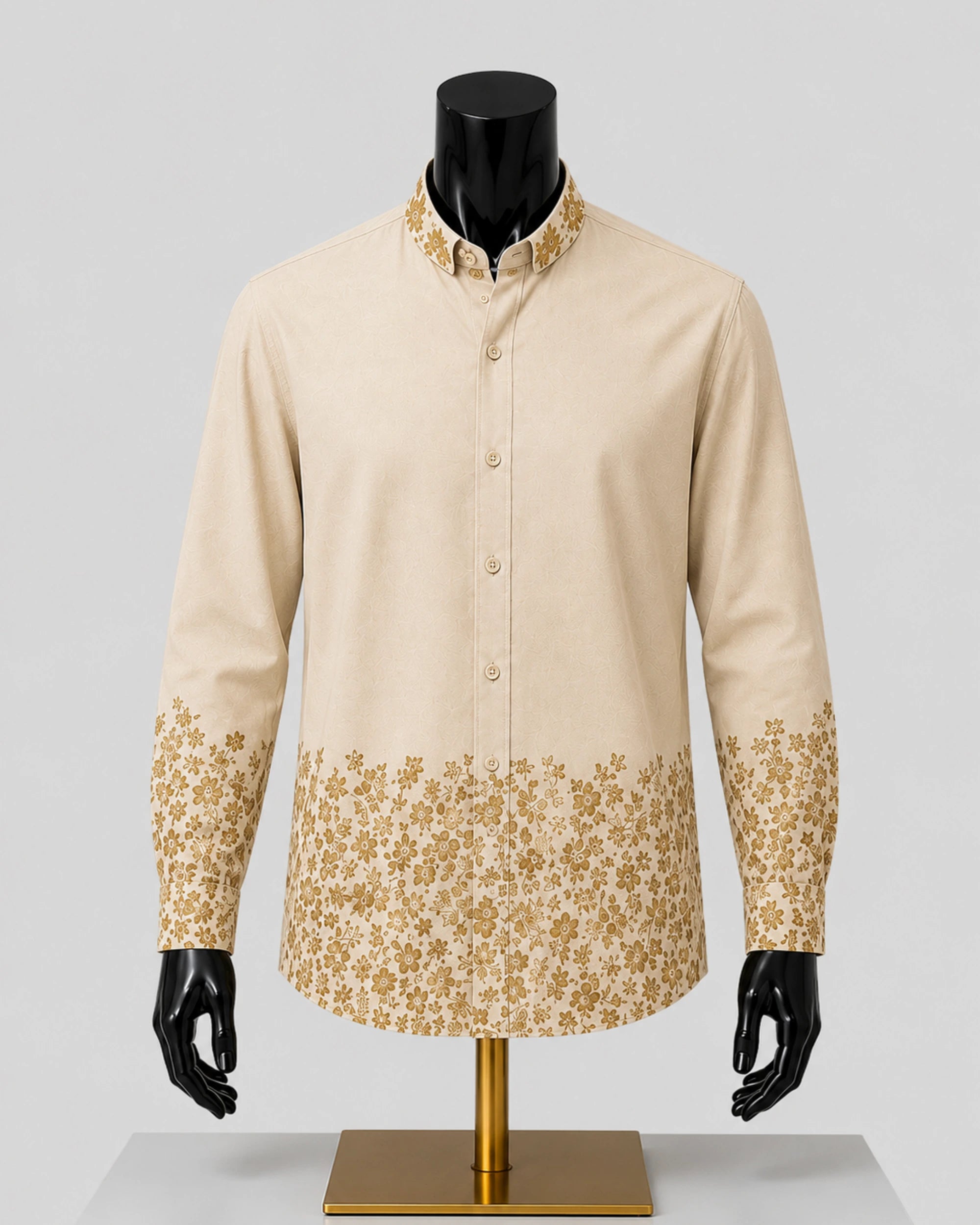 A men's long-sleeve button-up shirt in beige with a gold floral pattern along the collar, cuffs, and lower hem, displayed on a black mannequin torso with a gold stand against a light gray background.