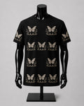 A black short-sleeve crewneck t-shirt displayed on a black mannequin torso. The shirt features an all-over repeating pattern of beige butterflies with floral details underneath.