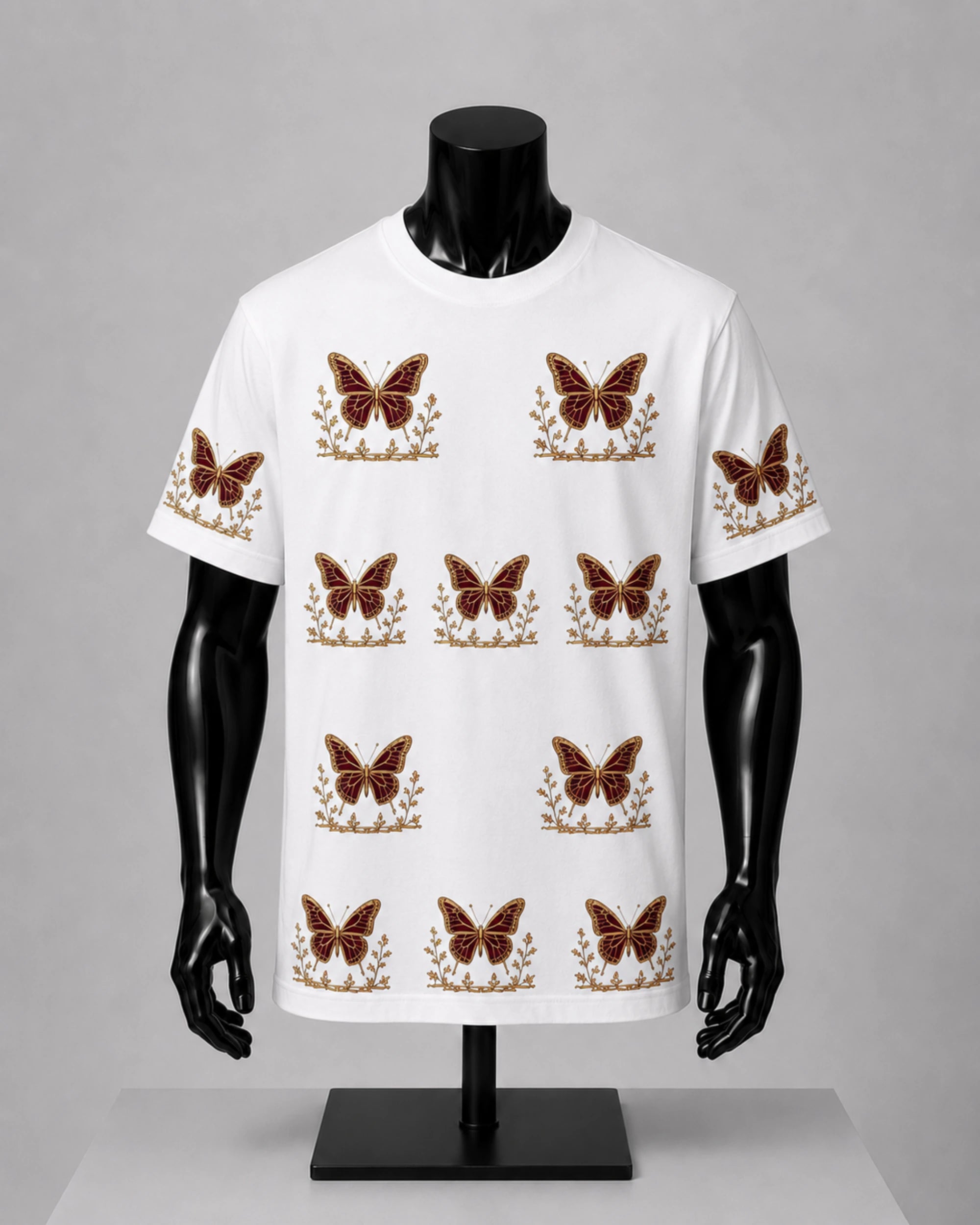 A white short-sleeve crewneck t-shirt displayed on a black mannequin torso. The shirt features a repeating pattern of brown butterflies with gold floral accents.
