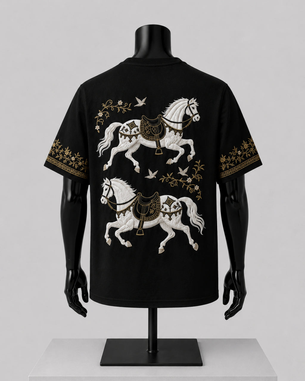 Black short-sleeve T-shirt displayed on a black mannequin torso, showing a large back print of two white horses with gold decorative details and small bird motifs.