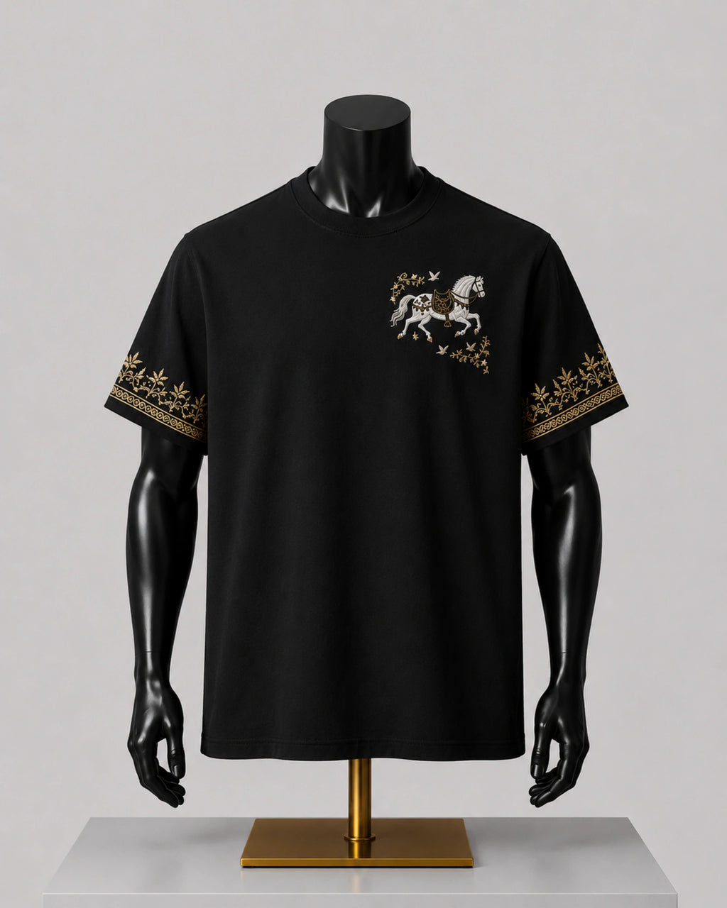 A black short-sleeve t-shirt displayed on a black mannequin torso with arms. The shirt features a small graphic of a white horse with gold detailing on the left chest and a gold patterned border on both sleeves.