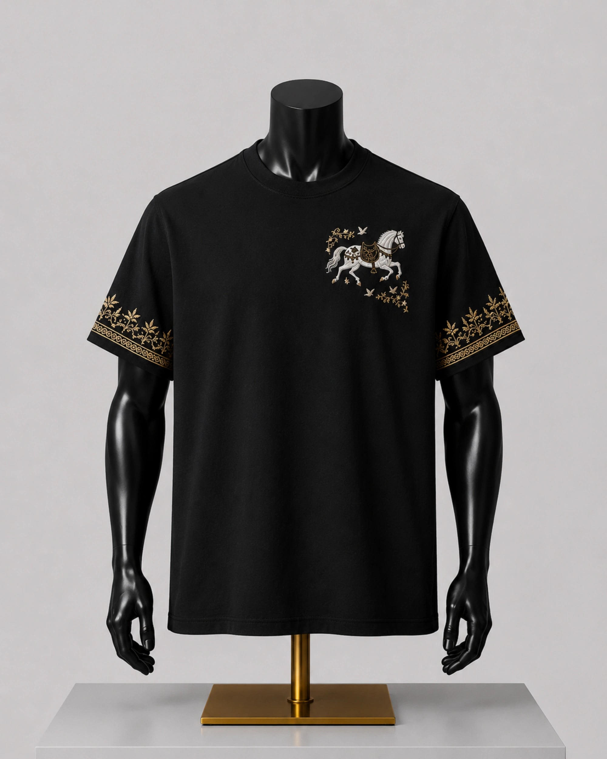 A black short-sleeve t-shirt displayed on a black mannequin torso with arms. The shirt features a small graphic of a white horse with gold detailing on the left chest and a gold patterned border on both sleeves.